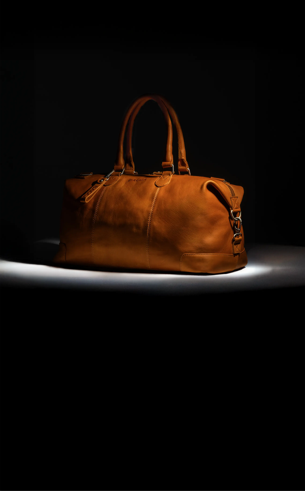 Cognac leren weekendtas van Bagga met dubbele handgrepen op zwarte achtergrond